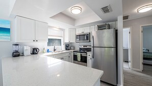 A modern kitchen with white cabinets, stainless steel appliances, and a large island.