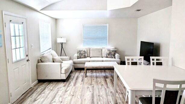 A modern living room with a white sofa, a coffee table, and a TV on a stand. - Spacious 2-bed, 2-bath second-floor unit near Indian Rocks Beach. Sleeps eight with full kitchen, WiFi, smart TV, shared pool access, and beach gear. A bright, comfortable base for families and groups looking for easy sand days and sunset evenings. (Indian Rocks Beach)
