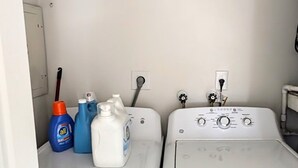 A laundry area with two washing machines and various cleaning supplies. - Spacious 2-bed, 2-bath second-floor unit near Indian Rocks Beach. Sleeps eight with full kitchen, WiFi, smart TV, shared pool access, and beach gear. A bright, comfortable base for families and groups looking for easy sand days and sunset evenings. (Indian Rocks Beach)