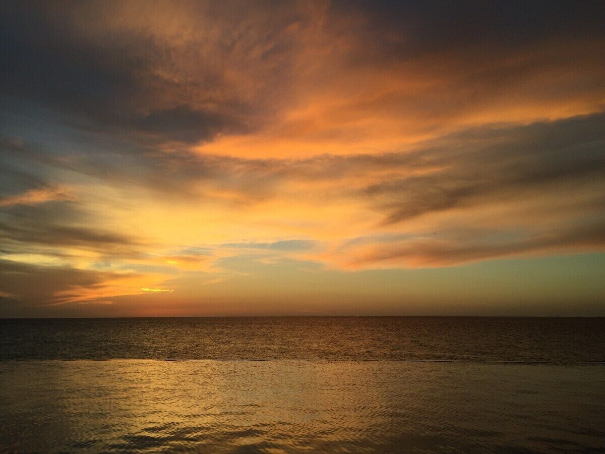 Un coucher de soleil sur une mer calme, avec un horizon dégagé.