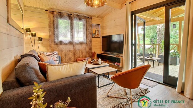 Een moderne woonkamer met een bank, televisie en een eethoek.