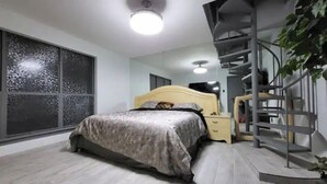 A bedroom with a bed, a nightstand, a TV, and a staircase. - Urban Treehouse (Dallas)