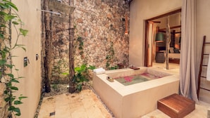 Un espace de détente avec un mur en pierre, une baignoire et un banc en bois.