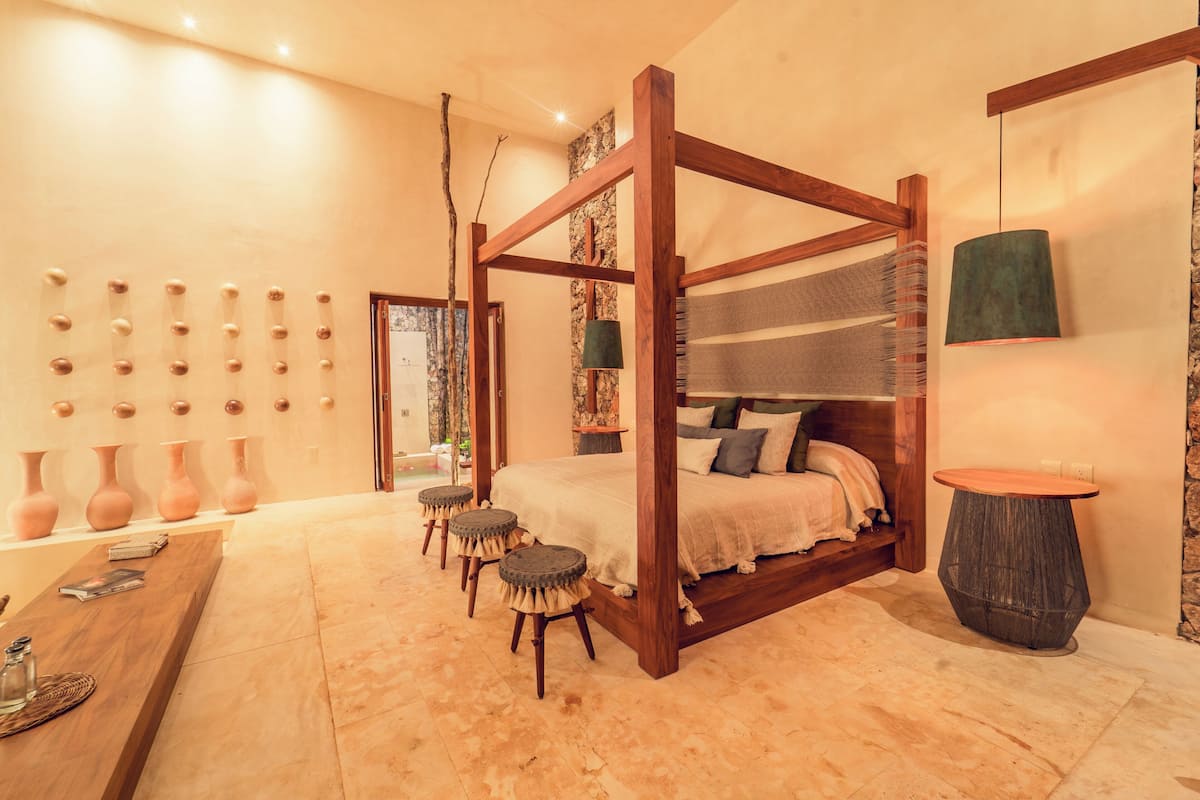 Un lit à baldaquin avec un cadre en bois, une table ronde et une collection de vases accrochés au mur.