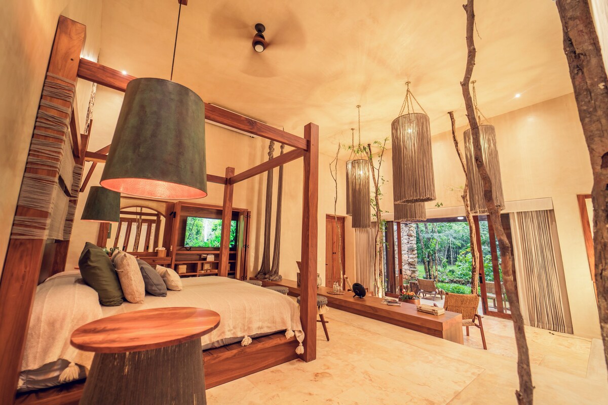 Een ruime slaapkamer met een groot bed, een houten hoofdbord, een televisie en uitzicht op de omgeving.