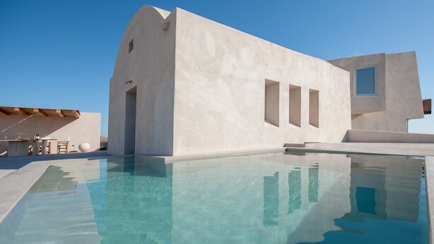 Un edificio moderno con piscina, que presenta un diseño minimalista y agua azul cristalina.