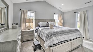 Un dormitorio con una cama grande, un aparador, una mesita de noche y una ventana con cortinas.
