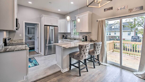 Una cocina moderna con gabinetes blancos, un refrigerador de acero inoxidable y una isla grande con taburetes de bar.