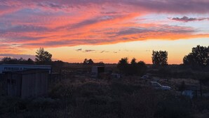 A rural landscape with a sunset sky, a sign reading "PENINSULA TRUCKS," and scattered buildings. - Wonderful campground in Caldwell with stunning views. And a shared private lake. (Caldwell)