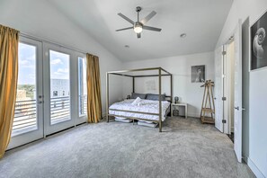 Ein Schlafzimmer mit Himmelbett, Deckenventilator und Blick durch große Schiebeglasfenster.