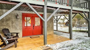 A covered porch with a red door, wooden chairs, and a stone-paved area. - Mountain Retreat < 4 Mi to Downtown Boone! (Boone)