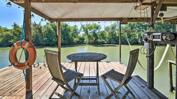 A wooden deck with a table and chairs overlooking a calm river, surrounded by lush greenery. - Bay Access & Dock: Riverfront Tivoli Escape (Tivoli)