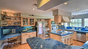 A modern kitchen with blue tiles, wooden cabinets, and stainless steel appliances. - Bay Access & Dock: Riverfront Tivoli Escape (Tivoli)