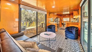 A modern interior with a sofa, two chairs, a small table, and a kitchen area with a dining table and chairs. - Hot Tub & Deck: Waterfront Escape in Payson! (Payson)