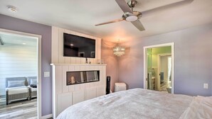 Una camera da letto con un letto, una TV a parete, una ventola a soffitto e un lampadario.
