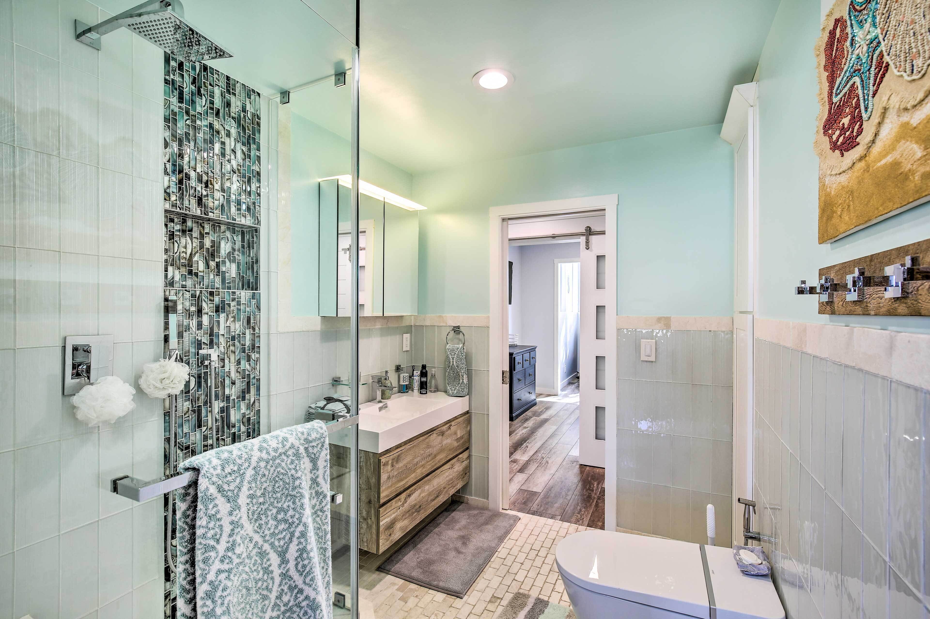 A modern bathroom with a glass shower enclosure, a vanity with a mirror, and a toilet.