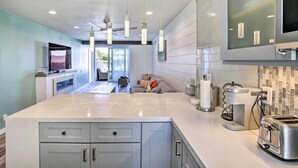 Una cucina moderna con una grande isola, elettrodomestici integrati e illuminazione a sospensione.