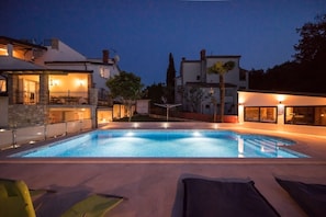 A swimming pool with a stone deck, surrounded by buildings with outdoor lighting. - Villa Vera Apt 1 - in House with Pool (Banjole)