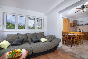 A living room with a sofa, a dining table with chairs, and a kitchen area.