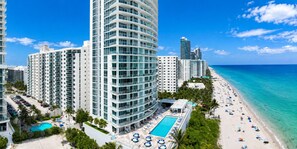 A beachfront hotel with a pool, multiple floors, and a beach view.
