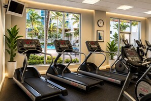 A fitness center with treadmills, exercise bikes, and a pool view. - Hollywood Oceanfront Condo| Ocean+ Pool Views| Sleeps 6| Game Room (Hollywood)