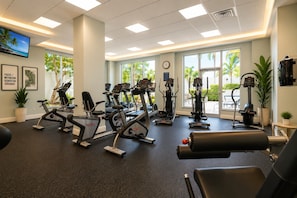 Ein Fitnessstudio mit verschiedenen Trainingsgeräten, großen Fenstern und motivierenden Wandbildern.
