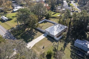 Vue aérienne d’un quartier résidentiel, avec une maison dotée d’un grand toit plat et d’une cour clôturée.