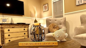 A round wooden coffee table with a candle and a decorative fish. - Snow Birds Welcome. 10 min to Downtown & Beach (St. Augustine)
