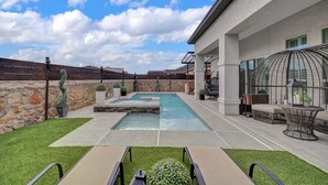 Une terrasse extérieure moderne avec une piscine, des murs en pierre et du mobilier d’extérieur.
