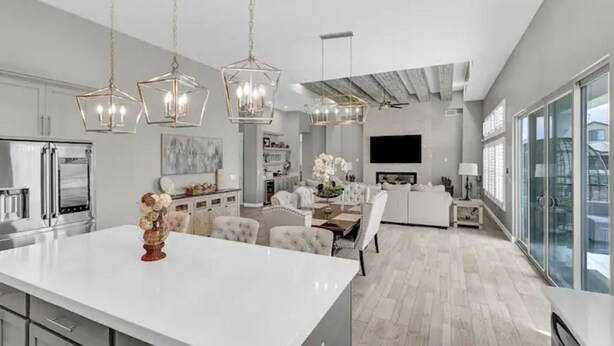 Une cuisine moderne avec des meubles blancs, un îlot central et des luminaires suspendus.