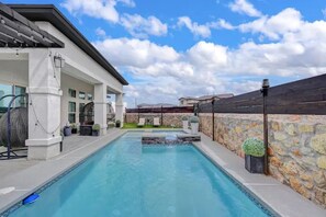 Piscina com muro de pedra e área coberta com assentos.