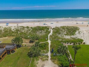 Vista aérea de una playa con un camino que conduce a un edificio con una terraza.