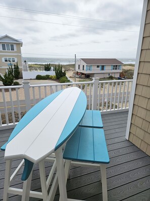 Guests can enjoy ocean views from this deck, which features a surfboard and a table.