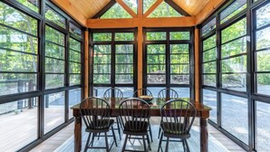 Un comedor con mesa y sillas de madera, ventanas amplias y vistas al exterior.