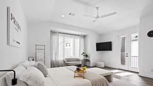 A modern bedroom with a bed, bedside table, and a TV mounted on the wall. - Modern Townhome near Galleria - Garage Gym / Private Backyard (Houston)