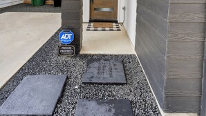 A modern house entrance with a wooden door, a concrete pathway, and a 'PRIVATE PROPERTY' sign. - Modern Townhome near Galleria - Garage Gym / Private Backyard (Houston)