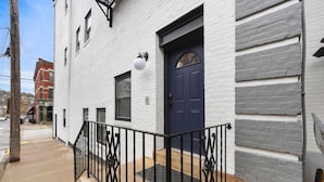 Un bâtiment blanc avec une porte bleue et une rambarde noire.