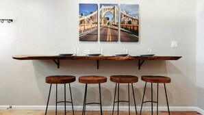 Een bar met een houten blad, vier krukken en drie ingelijste foto’s van een brug.