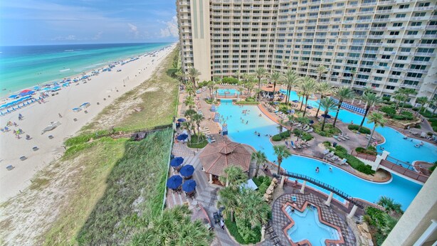 A resort with a beach, a large pool area, and a high-rise building.