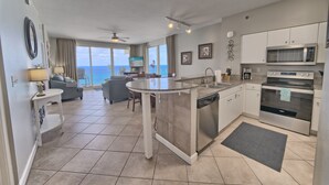 A modern kitchen with a central island, a dining area with a view, and a balcony with a view.