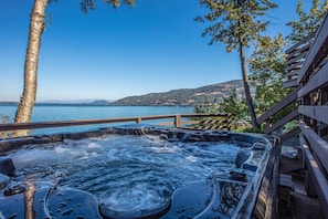 Ein Whirlpool mit Blick auf einen idyllischen See, einer Holzterrasse und blauem Himmel.