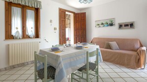 Un coin repas avec une table dressée pour quatre personnes, un canapé et une fenêtre avec des rideaux.