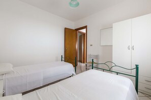 Une chambre avec deux lits simples, une armoire et un miroir.