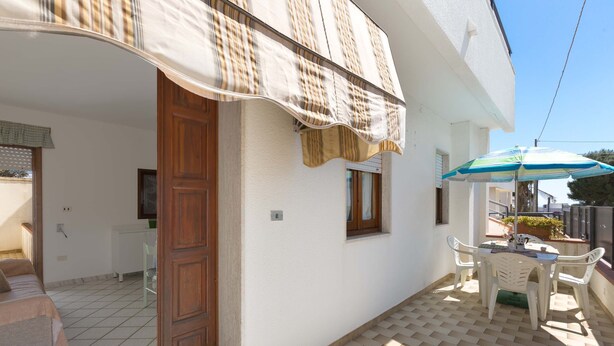 Une pièce avec un lit, une porte en bois, une fenêtre et une petite table avec des chaises.