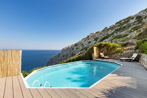 A swimming pool with a wooden deck, overlooking a rocky coastline and the sea. - 2098 Villa La Mecca by Perle di Puglia (Gagliano del Capo)