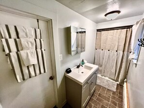 A bathroom with a sink, mirror, and shower curtain.