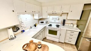A kitchen with white cabinets, a stainless steel refrigerator, a microwave, and a stove.