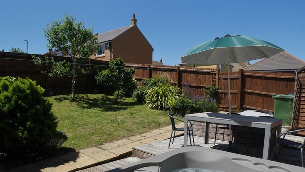 A backyard with a hot tub, patio furniture, and a wooden fence. - Cliffwalk Cottage (Portland)