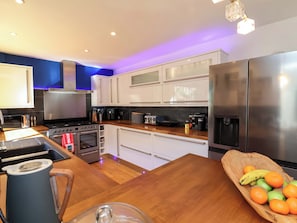 A modern kitchen with stainless steel appliances, wooden countertops, and a fruit bowl on the island.