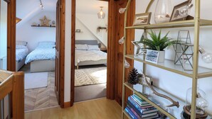 Een slaapkamer met een bed, nachtkastjes, een houten deur en een gang naar een andere kamer.